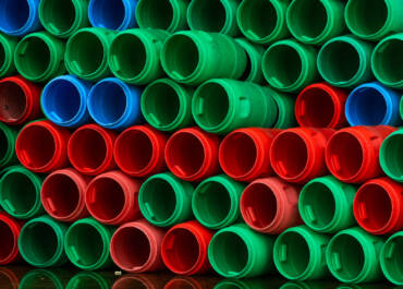 Used plastic barrels. Blue, green, and red plastic drum. Stacked of empty tank in food factory waiting for recycle and reuse. Container of raw material in food manufacturing industry. Old plastic drum